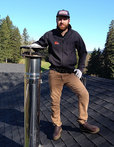 Marshal Schaefer, inspector with 45th Parallel, performing a roof inspection service while standing next to a chimney/venting pipe.