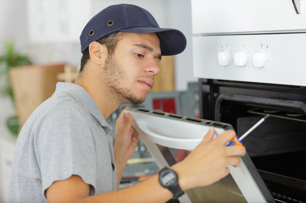 Professional repairman working on a kitchen oven