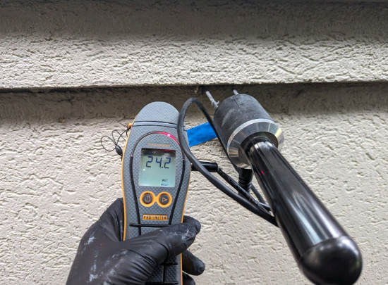 An invasive stucco inspection using a handheld probe going into the stucco.